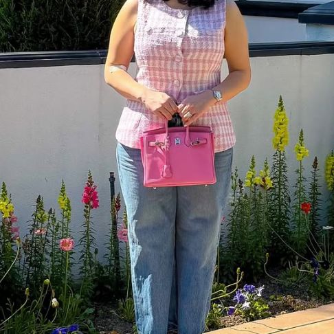 a woman in a pink sleeveless top and jeans holding a Pink Hermes Birkin 25